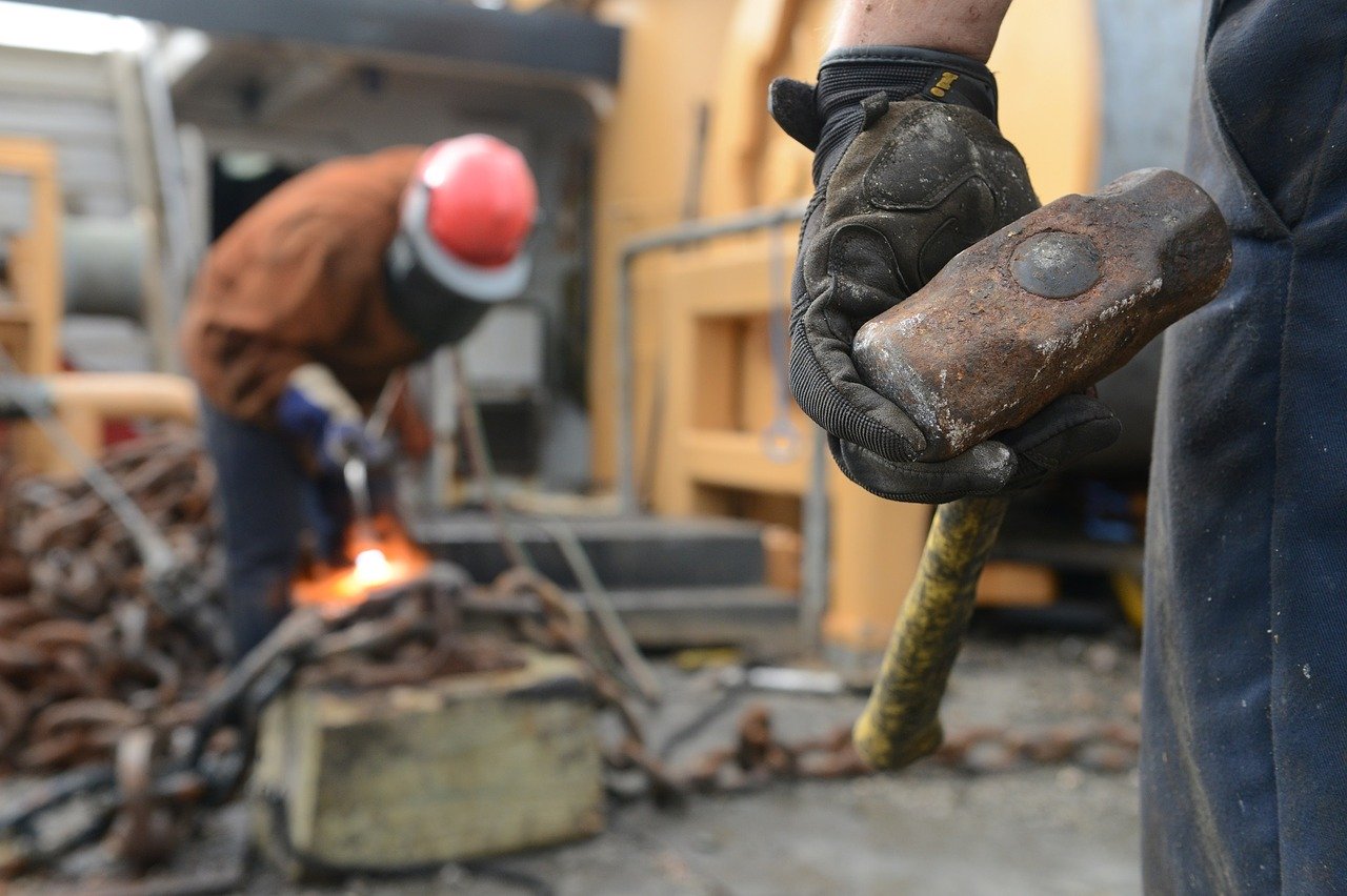 Worker with a hammer in his hand and another worker wielding in the background
